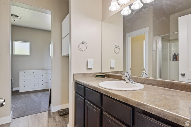 full bath with vanity, baseboards, a stall shower, and wood finished floors