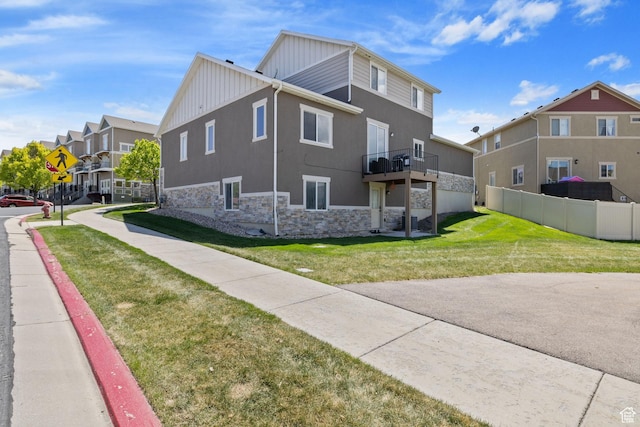 view of property exterior featuring fence, stone siding, stucco siding, board and batten siding, and a yard