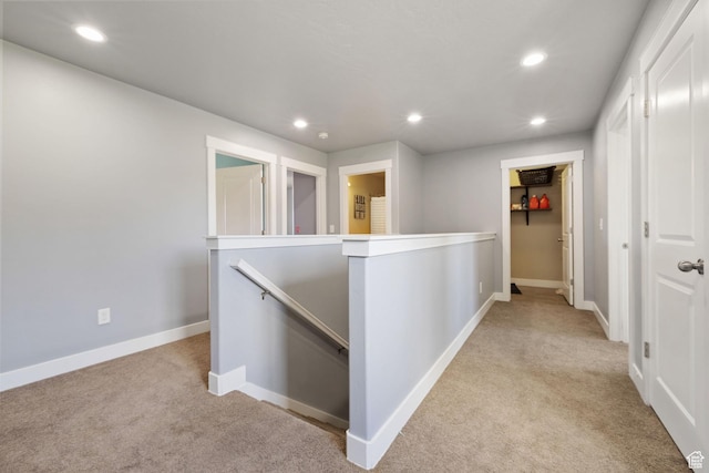 hall featuring recessed lighting, light carpet, and an upstairs landing