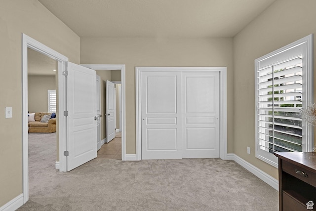 bedroom featuring baseboards, light colored carpet, and a closet