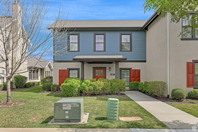 view of front of home featuring a front lawn, roof with shingles, and stucco siding