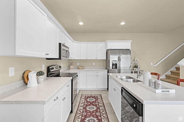 kitchen featuring white cabinets, appliances with stainless steel finishes, a sink, an island with sink, and light tile patterned floors