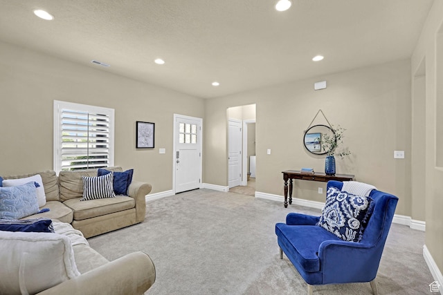 living room featuring light colored carpet, a healthy amount of sunlight, and visible vents