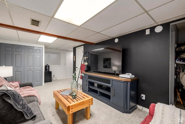 living area featuring visible vents, a paneled ceiling, baseboards, and light carpet