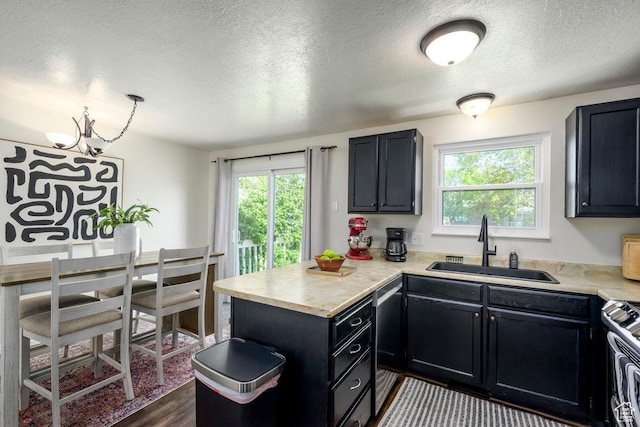 kitchen with a sink, light countertops, stainless steel appliances, and a peninsula