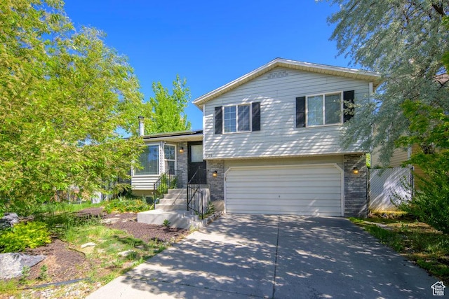 tri-level home with brick siding, driveway, and a garage