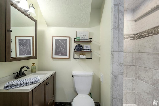 full bathroom with vanity, a tile shower, and toilet