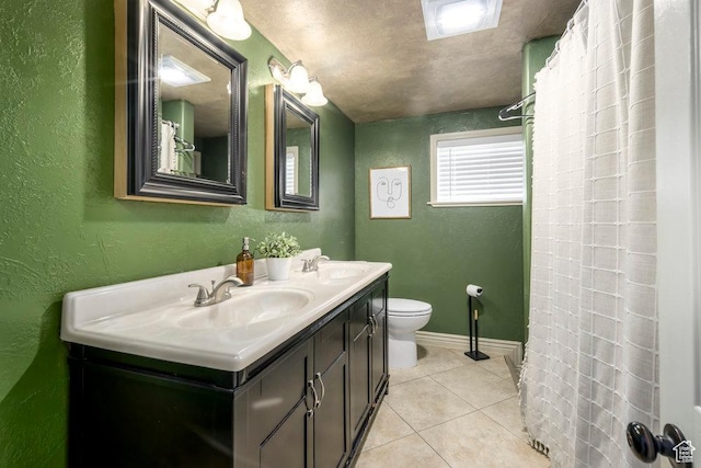 bathroom featuring tile patterned flooring, a sink, a textured wall, and toilet