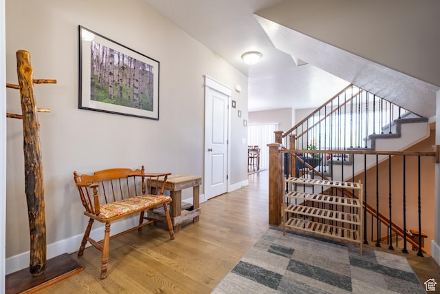 corridor featuring wood finished floors, baseboards, and stairway