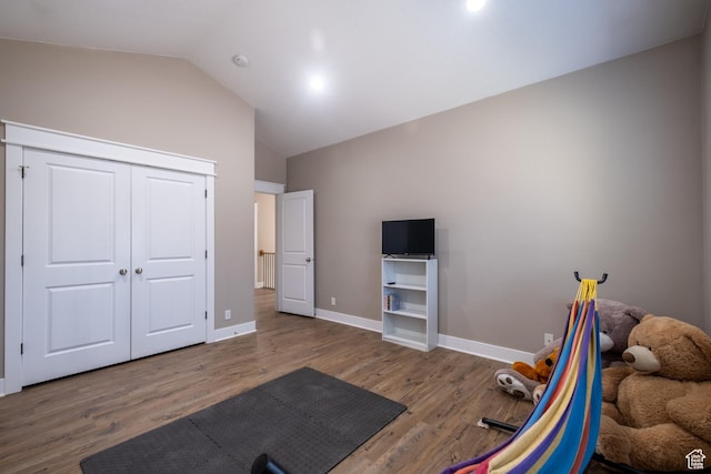 workout room with wood finished floors, lofted ceiling, and baseboards