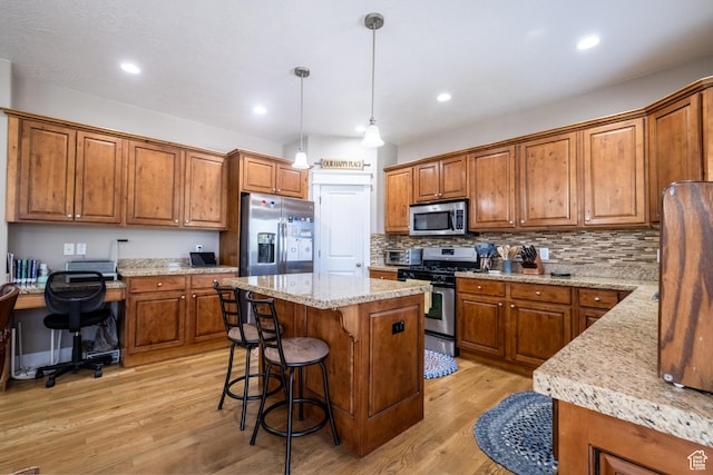 kitchen featuring stainless steel appliances, brown cabinets, a kitchen island, light wood-style flooring, and backsplash