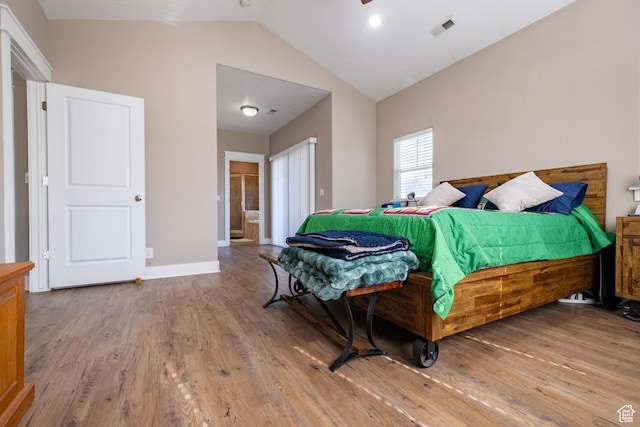bedroom with vaulted ceiling, wood finished floors, and baseboards