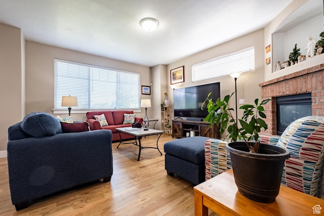 living room with light wood-style flooring and a brick fireplace