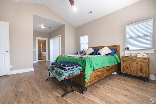 bedroom with lofted ceiling, wood finished floors, baseboards, ensuite bath, and ceiling fan