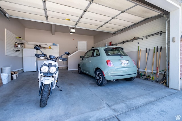 garage with a garage door opener, freestanding refrigerator, and baseboards