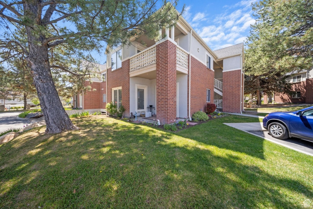view of property exterior with stucco siding, a yard, and brick siding