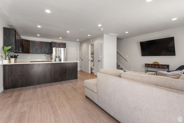 living area with stairs, recessed lighting, baseboards, and light wood finished floors