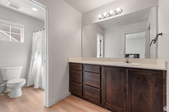bathroom with vanity, toilet, wood finished floors, and visible vents