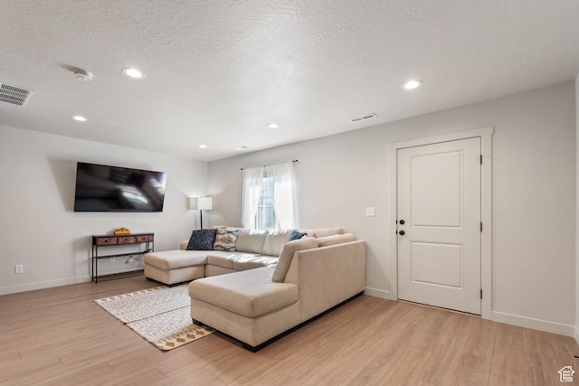 living room with recessed lighting, baseboards, light wood-type flooring, and visible vents