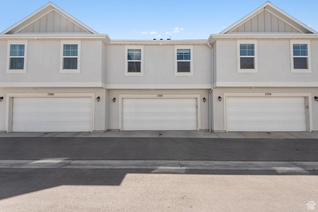 view of front of property featuring an attached garage, board and batten siding, and stucco siding