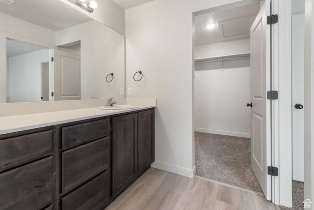 bathroom with vanity, baseboards, a walk in closet, and wood finished floors