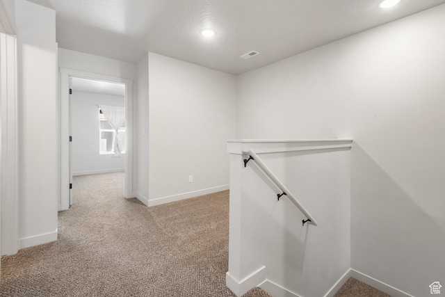 hallway featuring recessed lighting, an upstairs landing, and light carpet