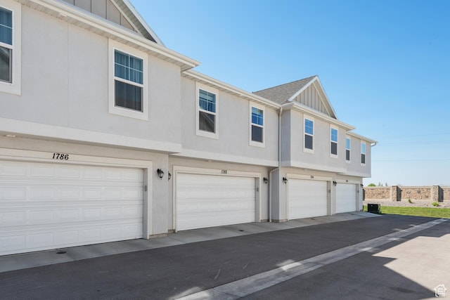 view of side of home featuring a garage, board and batten siding, and stucco siding