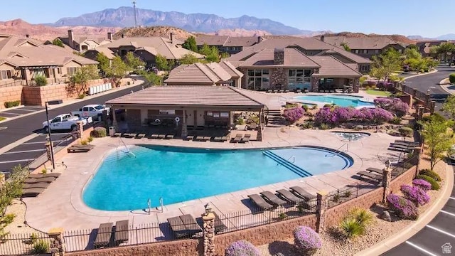 community pool featuring a patio area, a mountain view, fence, and a residential view