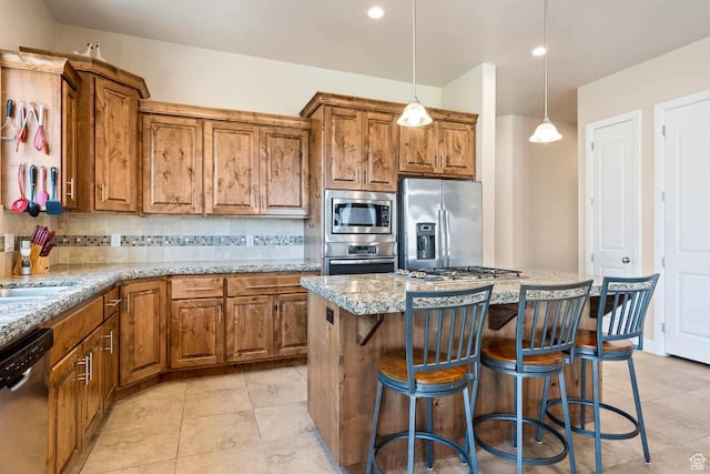 kitchen featuring tasteful backsplash, brown cabinetry, stainless steel appliances, and light stone countertops