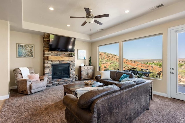 living room featuring carpet flooring, ceiling fan, a fireplace, baseboards, and visible vents