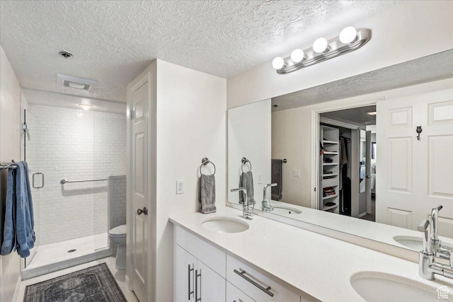 full bathroom with double vanity, a textured ceiling, a sink, and a stall shower