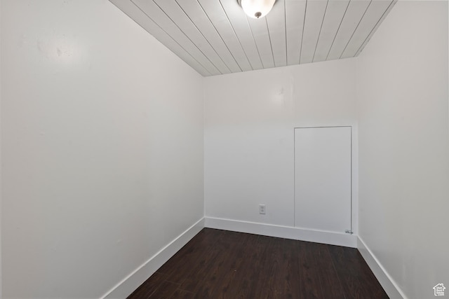 spare room featuring baseboards, dark wood-style floors, and wooden ceiling