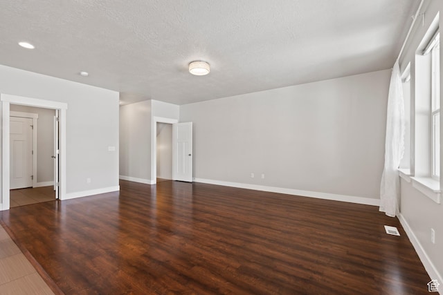 spare room with a textured ceiling, baseboards, visible vents, and wood finished floors