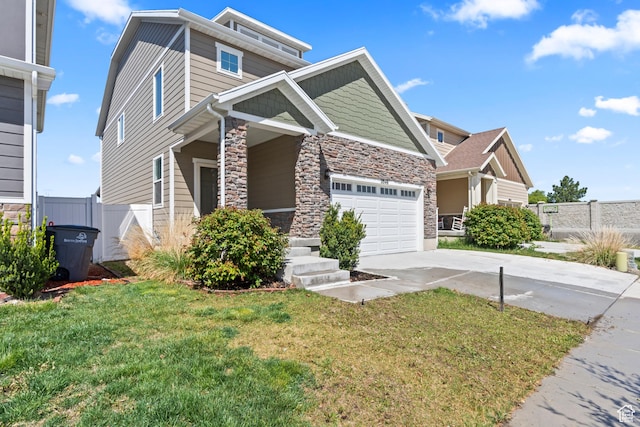 view of front of home with concrete driveway, fence, stone siding, and a front lawn