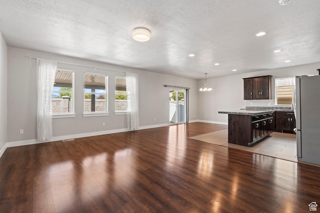 unfurnished living room with recessed lighting, light wood finished floors, a textured ceiling, and a notable chandelier