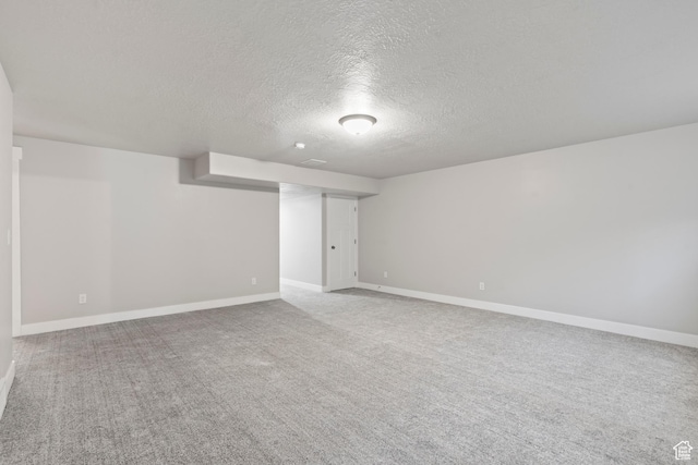 finished basement with carpet flooring, a textured ceiling, and baseboards
