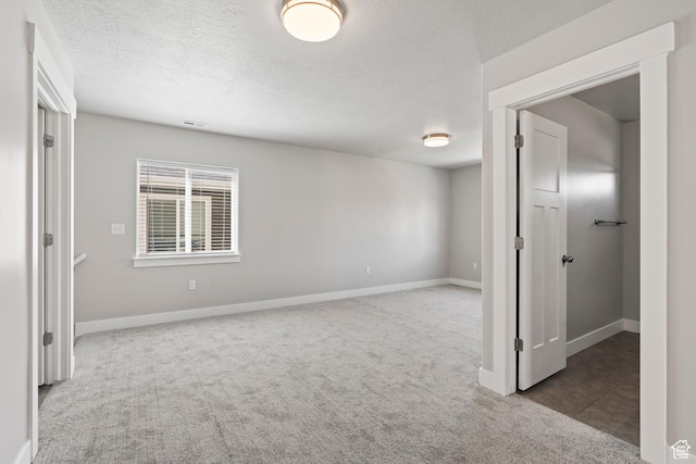 carpeted spare room featuring a textured ceiling, baseboards, and visible vents