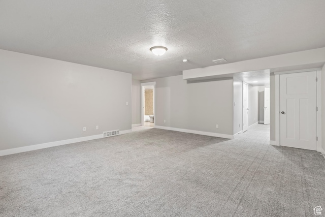 spare room featuring visible vents, carpet, a textured ceiling, and baseboards