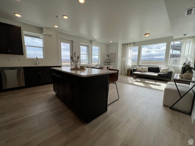 kitchen featuring visible vents, dishwasher, light countertops, a sink, and dark cabinets