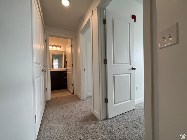 corridor featuring baseboards, light carpet, and visible vents
