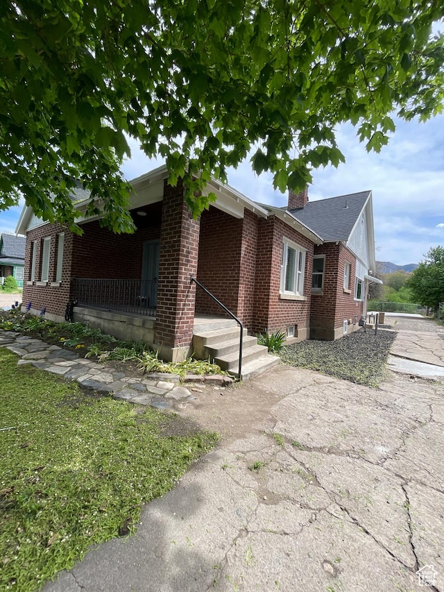 868 Washington Blvd, Ogden, UT 84404 - view of side of property featuring a chimney, a porch, and brick siding