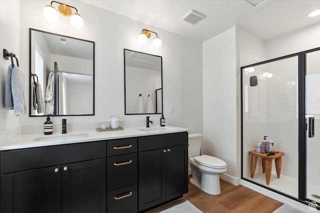 full bath with a sink, a shower stall, toilet, and wood finished floors