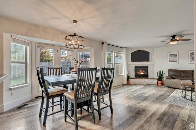 8983 N Barton Creek Dr, Eagle Mountain, UT 84005 - dining area with a large fireplace, baseboards, ceiling fan with notable chandelier, and light wood-type flooring