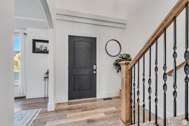 8983 N Barton Creek Dr, Eagle Mountain, UT 84005 - foyer entrance featuring light wood finished floors, arched walkways, baseboards, visible vents, and stairway