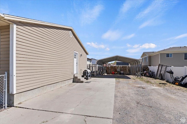 320 E Clark St, Grantsville, UT 84029 - view of side of home featuring concrete driveway, fence, entry steps, and a carport