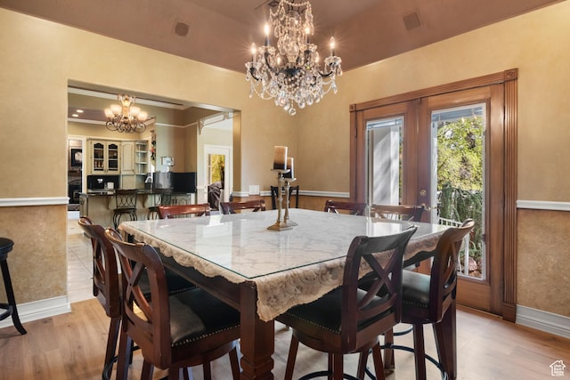 dining area featuring baseboards, french doors, light wood-style flooring, and a chandelier