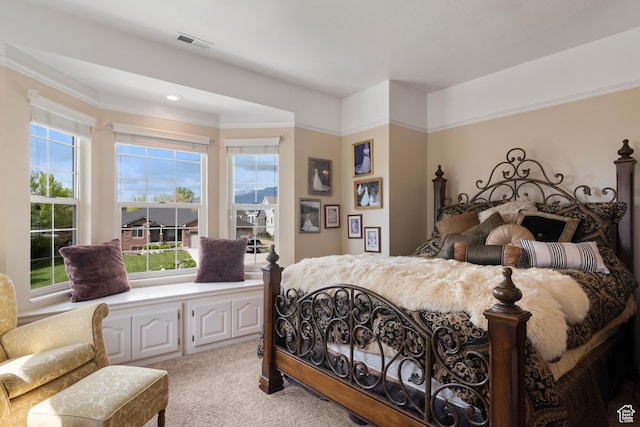 bedroom featuring visible vents, light carpet, ornamental molding, and multiple windows
