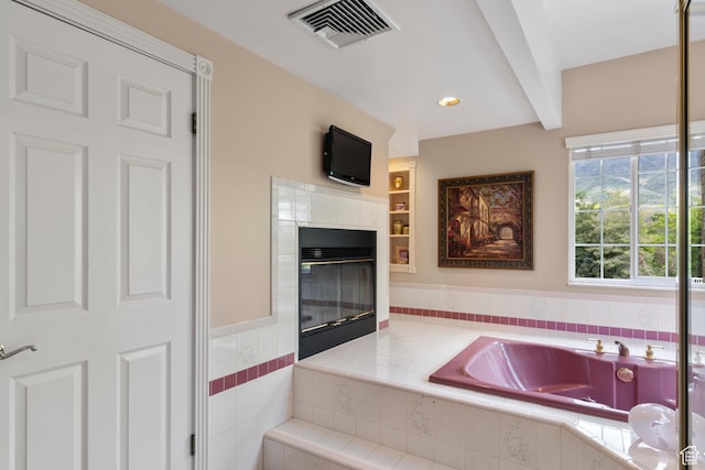 bathroom featuring visible vents, a bath, and a fireplace