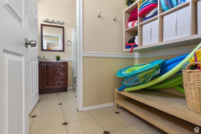 mudroom featuring baseboards, a sink, wainscoting, and light tile patterned flooring
