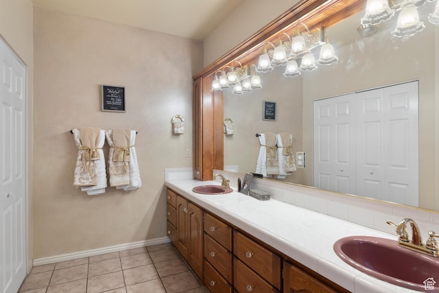 bathroom with a sink, tile patterned floors, baseboards, and double vanity